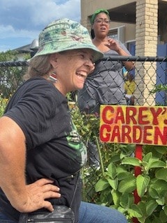 Lady gardener beside the Carey Garden sign at the Front Yard Farm